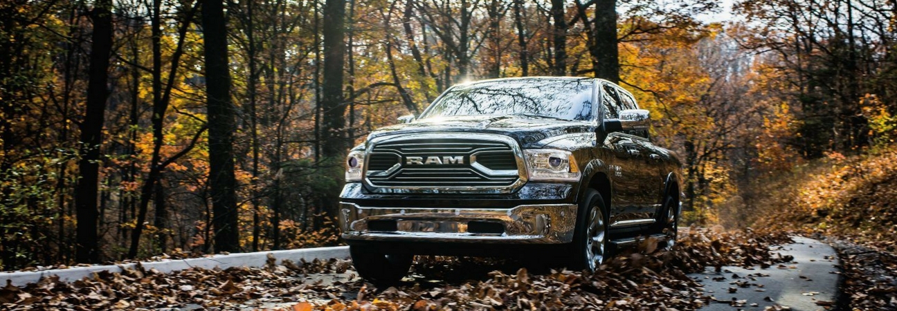 A 2018 RAM 1500 driving down a road covered in leaves