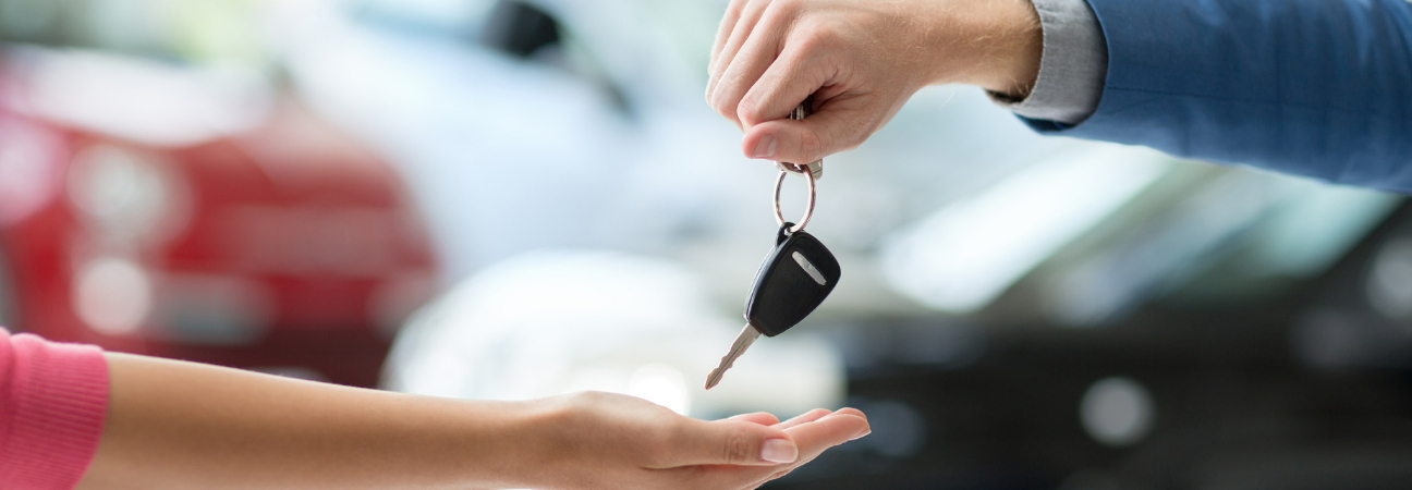 Dealership employee handing used car keys to customer